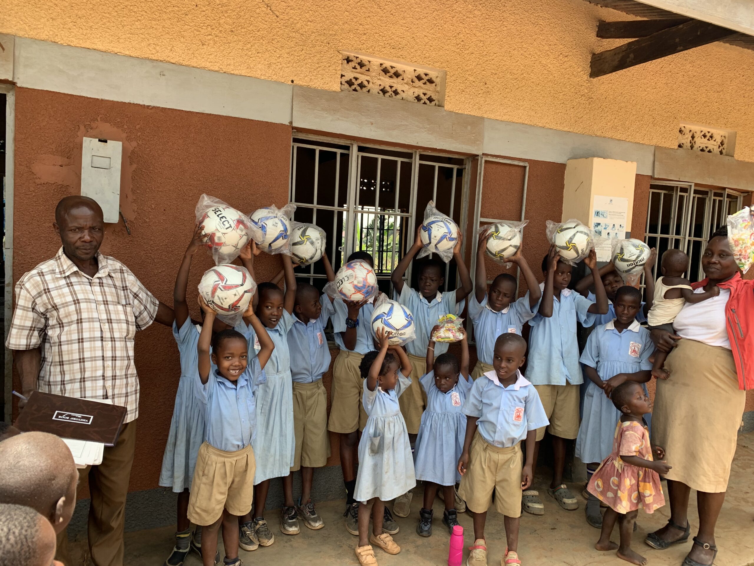 Children receiving footballs at a community outreach