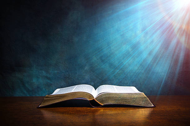 Open Bible on a wood table with light coming from above. ( church concept ).